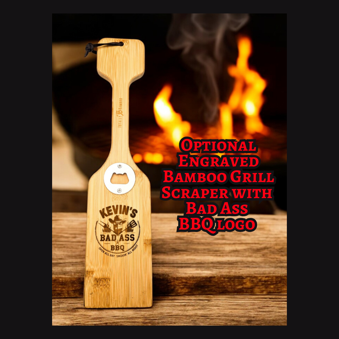 Engraved bamboo grill scraper with a built-in bottle opener, personalized with a “Bad Ass BBQ” logo and name, standing on a wooden surface with glowing grill flames and smoke in the background.