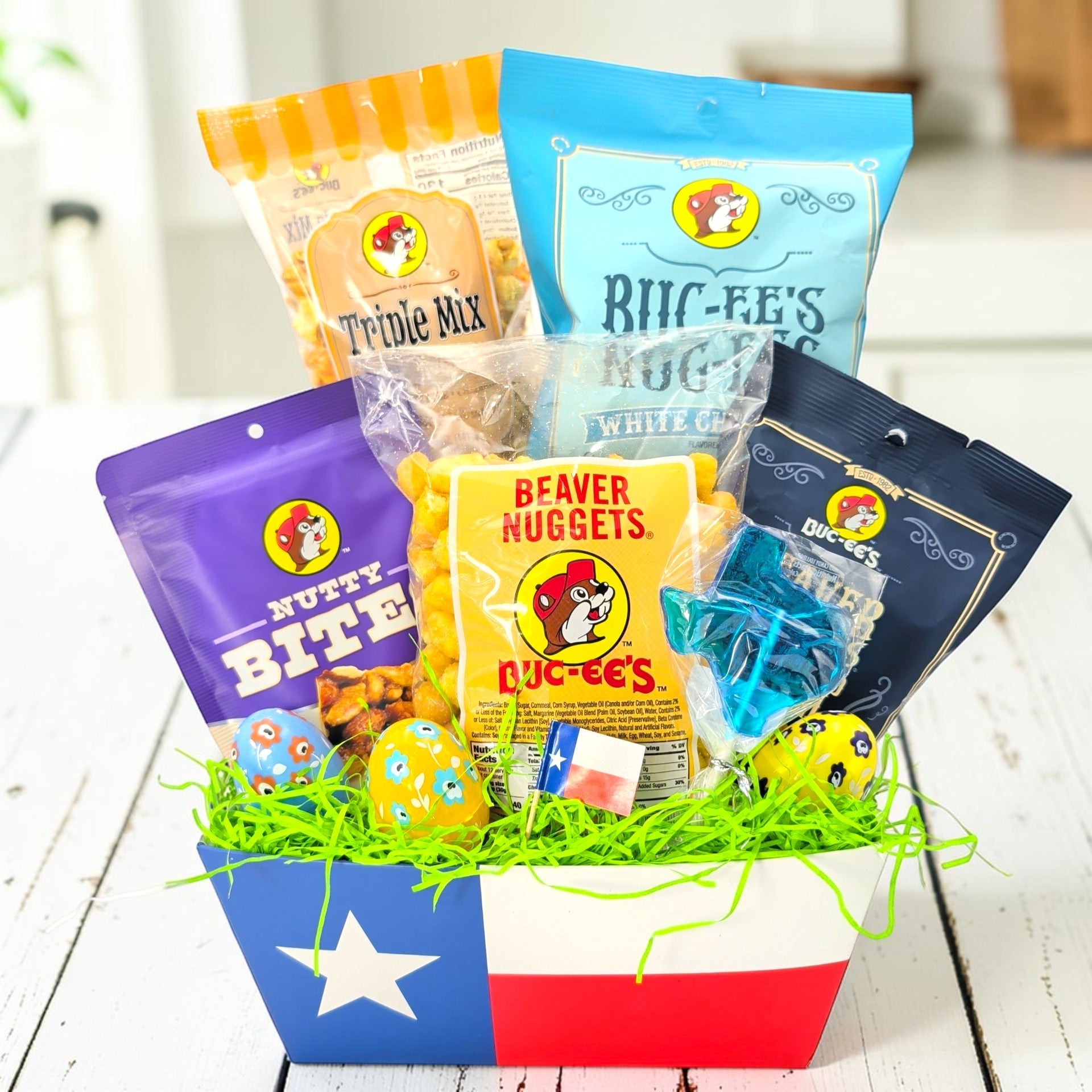 easter themed and buc-ees themed gift basket with various snack packages on a wooden surface