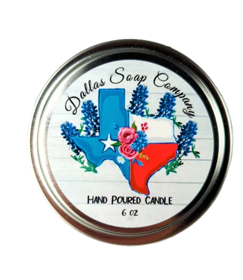 Top view of a Dallas Soap Company hand-poured candle tin featuring a Texas-shaped graphic with blue and red state colors, floral accents, and lavender illustrations, labeled as a 6 oz candle.