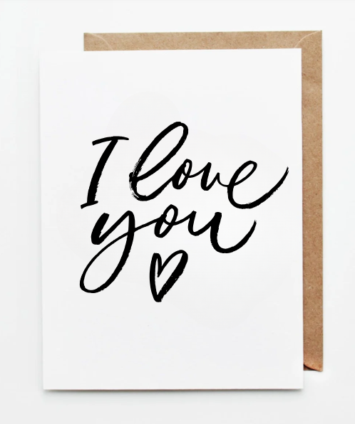 Minimal white greeting card featuring the handwritten phrase ‘I love you’ in black calligraphy with a small heart, paired with a kraft paper envelope