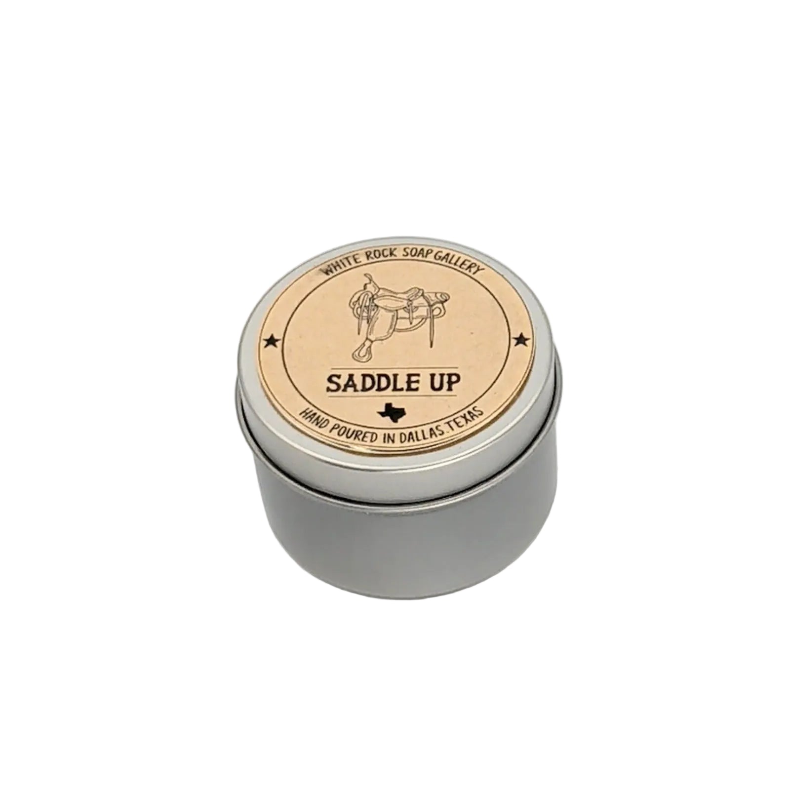 Round silver metal tin candle labeled “Saddle Up” by White Rock Soap Gallery, featuring a western saddle illustration and hand poured in Dallas, Texas, on a white background.