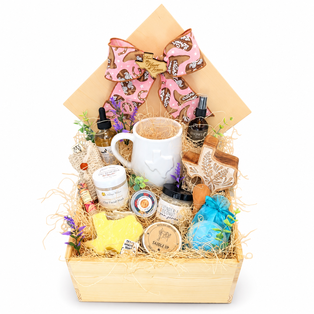 The Pampered Cowgirl wooden spa gift box with pink western bow, Texas mug, bath and body products, floral Texas keepsake box and wooden scoop on a white background.