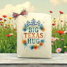 Big Texas Hug canvas gift bag with bluebonnet floral artwork, Texas-themed gift packaging displayed outdoors