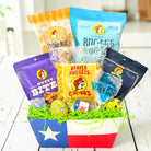 easter themed and buc-ees themed gift basket with various snack packages on a wooden surface