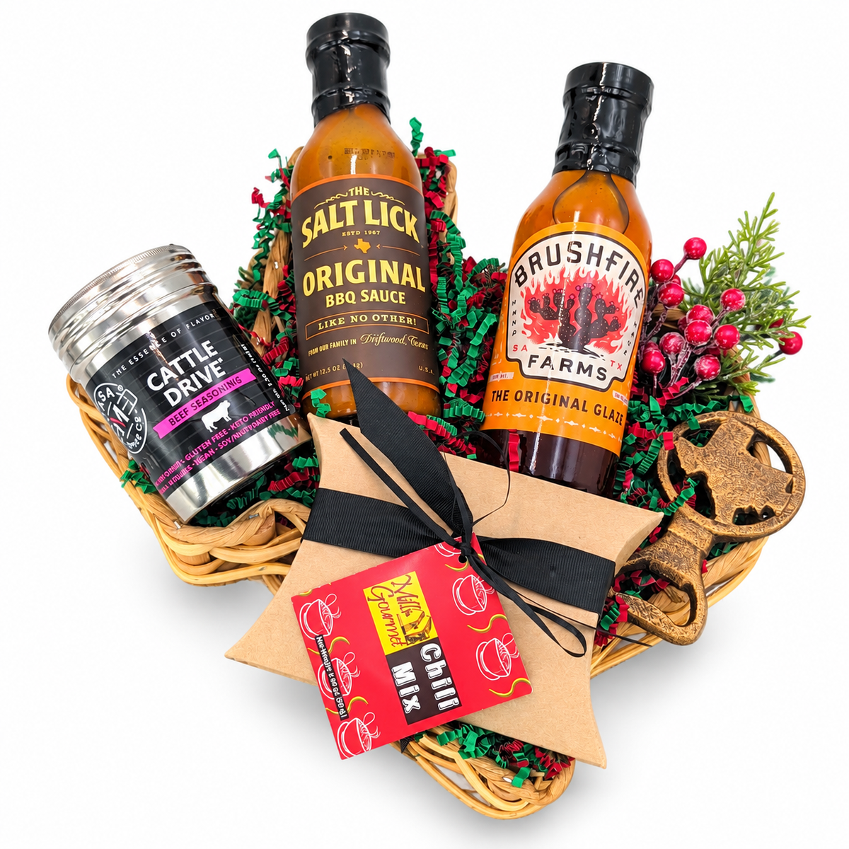 Texas Christmas Cookout, a Christmas selection of barbecue sauce, glaze, beef seasoning, chili mix and a Texas bottle opener in a Texas-shaped basket on white.