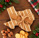 Texas-shaped charcuterie board and cheese spreader with Christmas greenery on a wood table