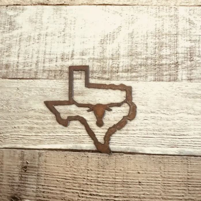 Rustic metal magnet featuring the Texas outline with longhorn design displayed as a Texas-themed keepsake from The Texas Gift Company storefront