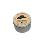 Small round metal tin candle labeled “Texas Suede” by White Rock Soap Gallery, hand poured in Dallas, Texas, photographed on a white background.
