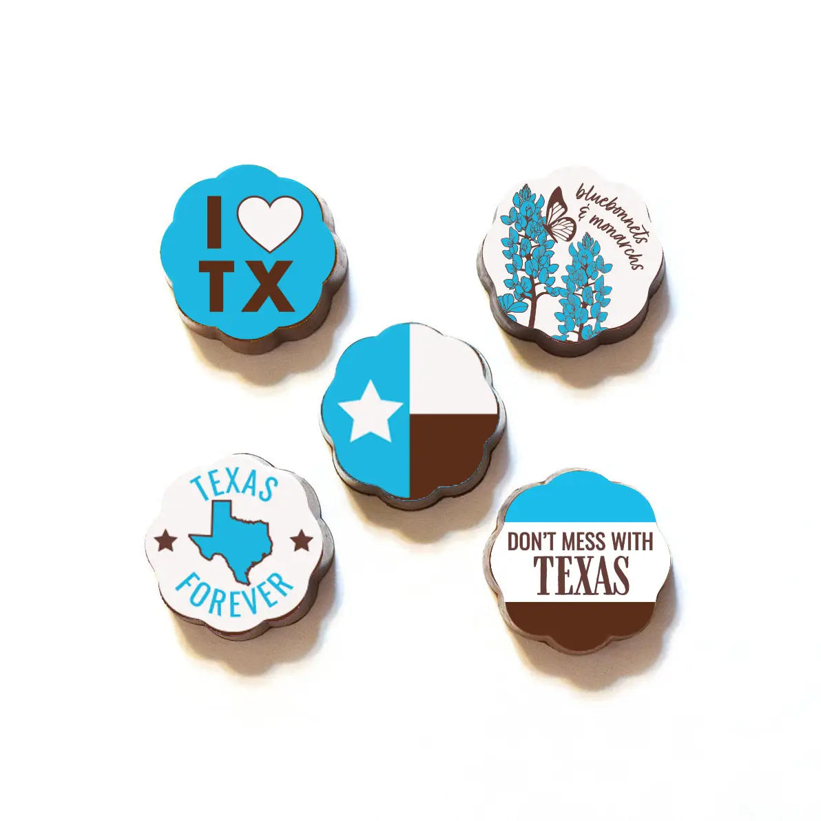 Assorted Texas-themed chocolate-covered caramels arranged on a white background, featuring designs such as “I Love TX,” Texas state flag, bluebonnets and monarch butterfly, “Texas Forever,” and “Don’t Mess With Texas.”